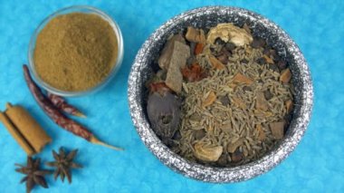 Hint mutfağından Khade Masala havan topağında karışık Hint baharatlarını ezmek. Tarçın çubukları, kurutulmuş kırmızı biber ve yıldız anasonu mutfak tezgahında bir arada tutulur.