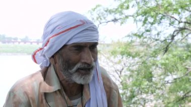 Hintli köylü akrabalarıyla kulaklıkla konuşmakla meşgul. Yaşlı, sakallı bir erkek bir ağacın gölgesinde otururken cep telefonuyla konuşuyor. Modern teknoloji.