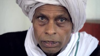 Kırsal Hintli köylüler boş zamanlarını yalnız oturarak geçirirler. Kameraya Safa pozu veren yaşlı bir adam.