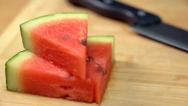 木のまな板に種を入れたジューシーなタルブジのクローズアップ 木製のテーブルに保持鋭いナイフで赤と熟したジューシーなTarboojのパンショット さわやかな果物 — ストック動画