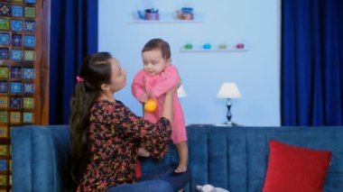 Genç Hintli anne bebeğine bakıyor. Küçük bir aile, sevgi dolu bir anne. Güzel bir bayan evde sevimli bir kızla oynuyor. Bebek bakımı, boş zaman, zaman yönetimi.