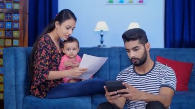 Hindistan 'daki küçük çekirdek aile, karı, koca ve kız. Aylık bütçe. Stresli karı koca günlük harcamalarını hesaplıyor. Finansal planlama, ev giderleri, aşırı harcama yok.