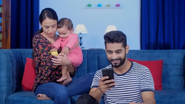 一个美丽的印度母亲和她的丈夫 并治愈了小宝宝 一个有爱心和关心家庭的丈夫 在家庭时间里使用手机 闲暇时间 电子产品 现代生活方式 — 图库视频影像