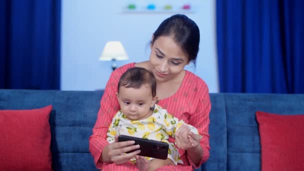 兴高采烈的印度母亲和她的小宝宝在手机上观看网上视频 卡通片 数字入侵 一个孩子在看手机 在孩子们的屏幕成瘾 闲暇时间 现代技术 屏幕时间 — 图库视频影像