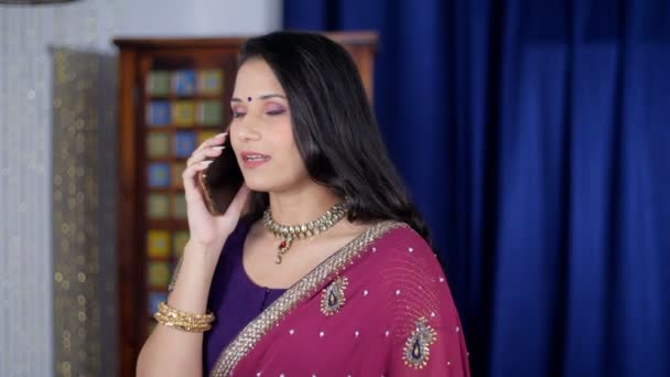 インドの伝統的なサリーを着た美しい北インド人女性がスマートフォンで話しています モバイルを使用して民族服のかなりプンジャビの女性 社会的な集まり 現代的なライフスタイル 電子機器 遠くの通信 — ストック動画