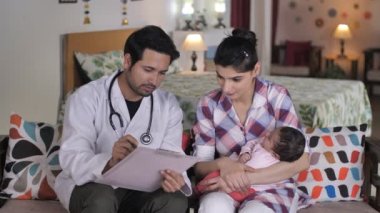 Evde genç bebek için tıbbi konsültasyon - Doktor ev ziyareti, doktor muayenesi, bebek kontrolü. Tatlı bir bebek annesinin kucağında huzur içinde uyuyor. Rahat, rahat bir uyku, anne-çocuk bağı.