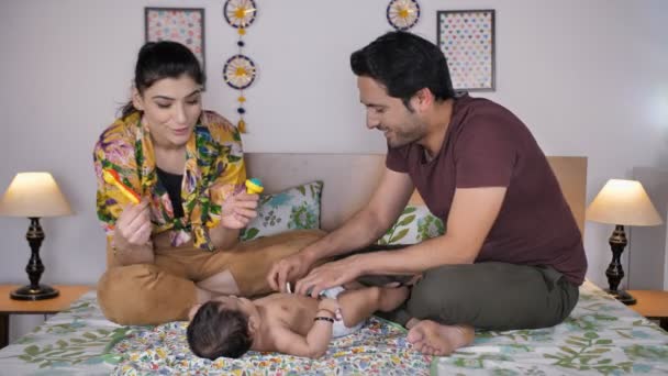 新しい親は彼らの赤ん坊と遊ぶ ボディマッサージ おなかの時間 子供のライフスタイル 若いインド人のカップルは娘と時間を過ごす レジャータイム 家族の絆 — ストック動画