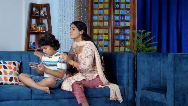 Счастливая Индийская Мать Расчесывает Волосы Своего Очаровательного Сына Дома Мальчик — стоковое видео