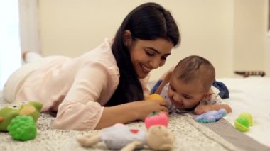 Bekar Hintli anne küçük oğluyla oynuyor. Yeni ebeveyn, çekirdek aile, çocuk bakımı. Güzel bir bayan hemşire ve evde yumuşak oyuncaklarla oynayan tatlı bir bebek. Güvenilir bir meslek, bebeklik, ilişki ve bağ.
