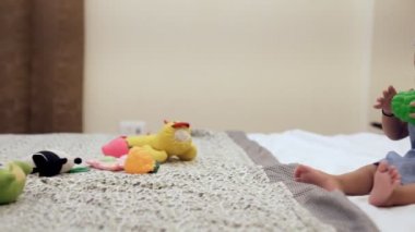 Sağlıklı gülümseyen bir kız bebek yatakta tek başına oturuyor. Uzağa bakarken yatakta oynayan neşeli, sevimli bir bebek. Bağımsız, boş zaman, keşif, iletişimin erken belirtileri.