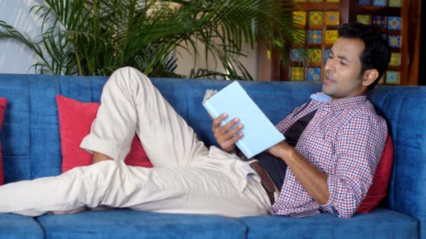 Індіанець Молодий Чоловік Який Читає Книжку Відпочиваючи Дивані Вітальні Студент — стокове відео