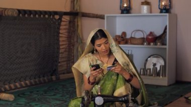 Hint köyündeki modern ve eğitimli bir kadın geleneksel bir Saree 'de bankamatik kartı kullanan çekici bir Hintli köylü. Evli bir ev hanımı cep telefonuyla online alışveriş yapıyor. Yeni teknoloji, dijital Hindistan, eğitimli bir köy kadını.