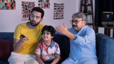 Üç nesildir televizyon seyreden aile üyeleri. Aile bağı, kaliteli zaman geçirme, ekran kullanımı, ortak aile. Uzaktan kumandayı kullanan zeki bir genç - torun, elektronik cihaz, modern yaşam tarzı