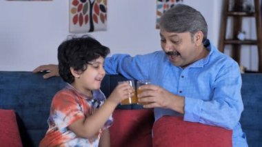 Genç bir çocuk ve günlük giysiler içinde yaşlı bir adam birlikte meyve suyu içmekten zevk alıyorlar. Sevimli bir torun ve büyükbabası rahat bir kanepede otururken birlikte vakit geçiriyorlar. Oturma odası, boş zaman, yaz tatili.