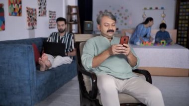 Evde Hintli bir aile var. Bir karede üç nesil. Yaşlı adam cep telefonunu karıştırıyor. Yatakta otururken küçük oğluyla oynayan güzel bir anne. Boş zaman, ebeveyn-çocuk bağı, sevgi ve şefkat.