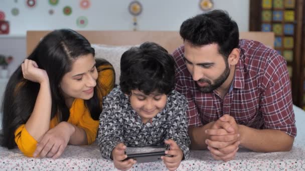 Happy Indian Family Using Smartphone Together While Lying Bed Nuclear — Stock Video