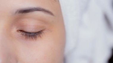 Bir kadın gözünün yakın çekimi - iyi görüş, optik görüş, cilt bakımı, güzel gözler, göz kapağı. Saçlarını havluya sarmış güzel bir kadının yarım yüzü.