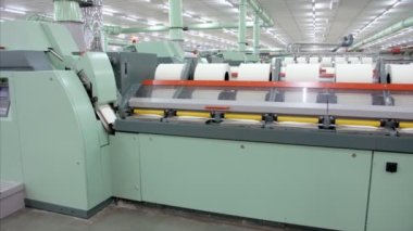 Tekstil fabrikasındaki teknik otomasyon. Giyim endüstrisinde kullanılan iplik makinesi. Bir kumaş imalat atölyesinde çalışan elektronik bir makinenin yakın plan çekimi - teknoloji konsepti