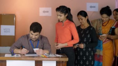 Seçmen kimliğini kontrol eden erkek bir seçim memuru. Oy pusulaları, kimlik belgeleri, bir Hint vatandaşı, Hint parlamento seçimleri, oy kabini. Adaylar oy vermek için sırada bekliyorlar - belediye seçimleri, sandık kulübesi...