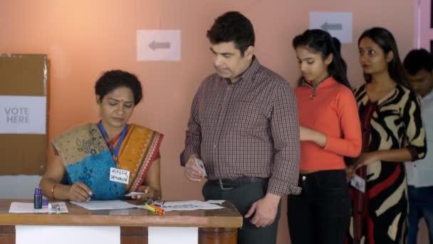 投票者の身分証明書 新しい有権者 インド市民 幸せな有権者のグループと選挙担当官は親指アップジェスチャーを行います 中年の女性役員 Chunaav Adhikaariは 投票所で彼女の机で働いています 自治体選挙 投票センター — ストック動画