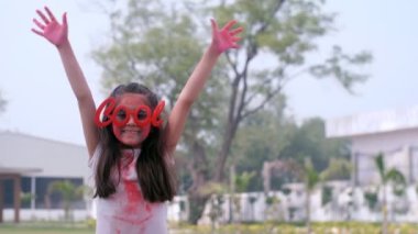 Genç bir okul çocuğu avuçlarının tozla kaplı olduğunu göstermek için heyecanlı Holi festivali, renkli eller, organik Gulal. Moda güneş gözlüğü takan ve halka açık bir parkta kameraya poz veren sevimli, küçük bir kız....