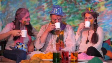 Pudra rengine bulanmış neşeli Hintli gençler ve neşeli Holi Festivali 'ni kutluyorlar. Bir grup genç arkadaş çay içerken birbirlerine 