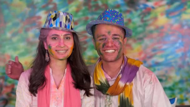 かわいいインドのカップルは ハッピーホリがビデオ通話で友人や親戚に 美しく 絆を願っています 笑顔のカップルは 色のインドの祭りを祝いながら カメラのポーズ ハッピーフェイス 祭りの時間 — ストック動画