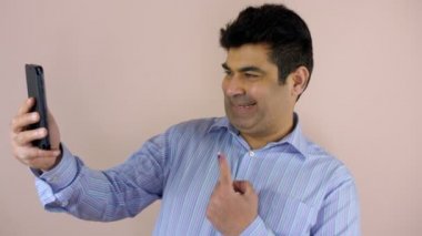 Seçimlerde oy verdikten sonra cep telefonuna selfie çeken orta yaşlı bir adam. Eyalet seçimleri, Hint vatandaşı, demokratik bir ülke. Formaliteler içinde şık giyinmiş bir adam sol elinde dövmeli parmağını gösteriyor. Kayıtlı bir seçmen, bir funda....