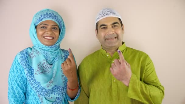 民族衣装を着たイスラム教徒のカップルは 州の選挙 登録有権者 身分証明書のマークなど 彼らのインクマークの人差し指を一緒に示しています インド市民 基本的権利 再投票後にカメラに向かっている現代のインドの家族 — ストック動画
