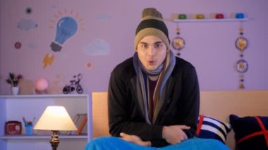 Çekici genç bir adam, video çağrısında insanları selamlarken elini sallıyor. Uzak iletişim, internet teknolojisi, modern yaşam tarzı.