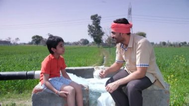 Sevgi dolu bir baba / Hintli köylü ve küçük sevimli oğlu - mutlu bir ebeveyn-çocuk bağı, sevgi ve şefkat. Sakallı bir çiftçi ve tatlı çocuğu birlikte bir hardal / Sarso tarlasında vakit geçiriyorlar - tarım tarlalarında.