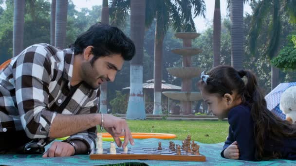 一个年轻人和一个可爱的小女孩在下棋 棋盘游戏 一个竞争激烈的游戏 好玩的时间 一对印度父女二人在公园共度美好时光 闲暇时间 亲子关系 — 图库视频影像