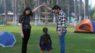 Çekici bir Hintli çift ve küçük kızları birlikte oyun oynuyorlar. Bir çocukluk oyunu, mutlu bir çocukluk. Çiftlik evinde nükleer Hint aile pikniği - eğlence aktivitesi, şehir parkı, boş zaman, aile bağı