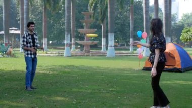Yakışıklı bir adam ve güzel bir kadın birlikte sarı frizbiyle oynuyorlar. Açık hava sporu, plastik disk. Evli bir Hintli çift halka açık bir parkta birlikte eğleniyor. Boş zaman, çiftler arası bağ, ilişki ve birliktelik.