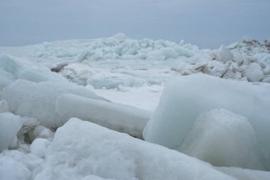 Donmuş deniz. Kıyıda yığılmış kocaman buz kalıpları. Kumsalda fırtınalı hava.