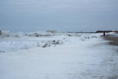 Donmuş deniz. Kıyıda yığılmış kocaman buz kalıpları. Kumsalda fırtınalı hava.