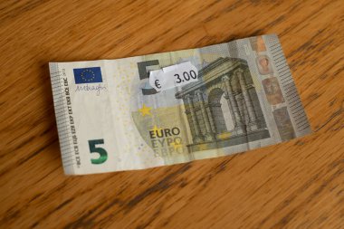 Beş euro banknot ve üç euro fiyat etiketi. Etikete seçici odaklanma.
