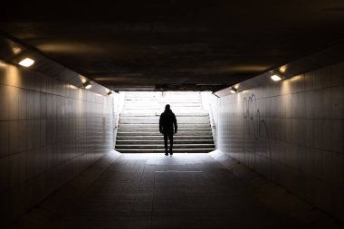 Karanlık yeraltı tünelinde yürüyen bir adam. Yabancı anonim kişi.