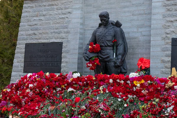 Tallinn, Estonya - 12 Mayıs 2022: Bronz Asker (est: Pronkssdur) anıtı. Kızıl Ordu gazileri Zafer Günü 'nü kutladılar. Kırmızı karanfil çiçekleri getirdiler..