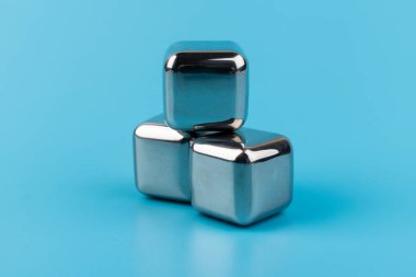 Mavi arka planda izole edilmiş paslanmaz çelik buz küpleri viski taşları. Metin için boşluk.