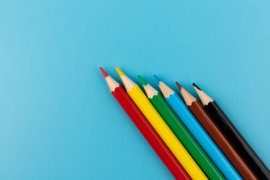 Parlak mavi bir arka plan üzerinde renkli kalemler ile kompozisyon. üstten görünüm. text.frame mekanı