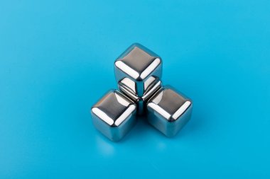 Mavi arka planda izole edilmiş paslanmaz çelik buz küpleri viski taşları. Metin için boşluk.