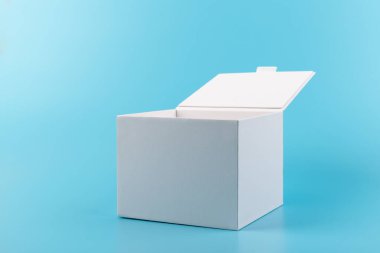 Mavi arka planda beyaz karton kutu açılmış. Tasarım için yer.