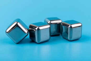 Mavi arka planda izole edilmiş paslanmaz çelik buz küpleri viski taşları. Metin için boşluk.