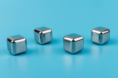 Mavi arka planda izole edilmiş paslanmaz çelik buz küpleri viski taşları. Metin için boşluk.