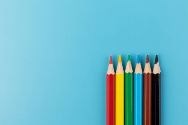 Parlak mavi bir arka plan üzerinde renkli kalemler ile kompozisyon. üstten görünüm. text.frame mekanı