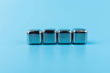 Mavi arka planda izole edilmiş paslanmaz çelik buz küpleri viski taşları. Metin için boşluk.