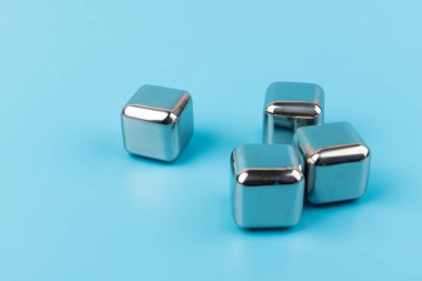 Mavi arka planda izole edilmiş paslanmaz çelik buz küpleri viski taşları. Metin için boşluk.