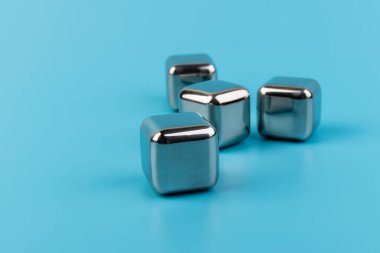 Mavi arka planda izole edilmiş paslanmaz çelik buz küpleri viski taşları. Metin için boşluk.