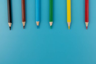 Parlak mavi bir arka plan üzerinde renkli kalemler ile kompozisyon. üstten görünüm. text.frame mekanı